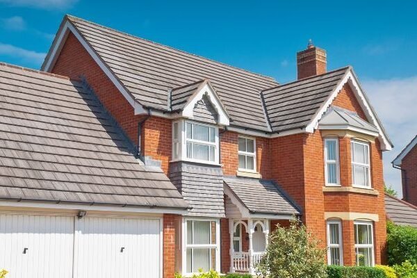 Red brick residential property with newly installed grey tiled pitched roof - roofing services