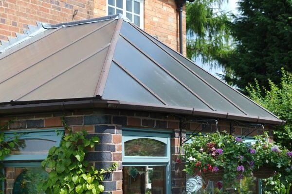 Grey tiled conservatory roof on red brick extension with garden view